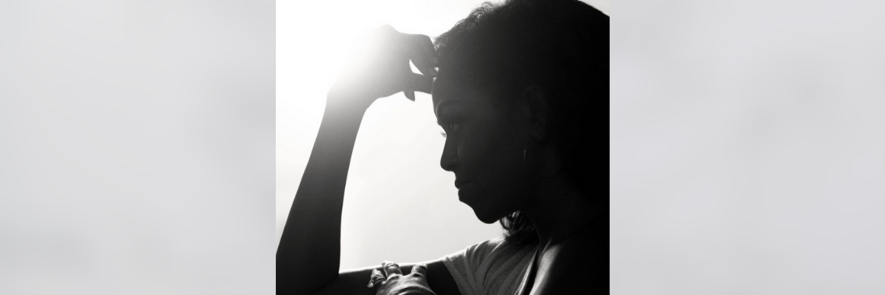 Black and white profile of Michelle Obama with her hand on her head