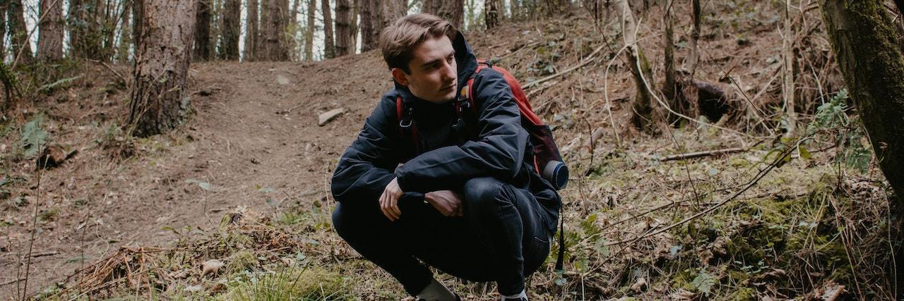 How to Cope With Isolation When You Have Bipolar Disorder Young man squatting look into the forest