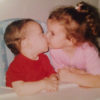 Abby as a small child, giving her brother a kiss.