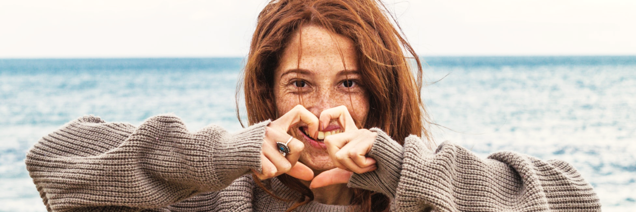 Chronic Pain: What's Hidden Behind My Smile Woman with ocean behind her.