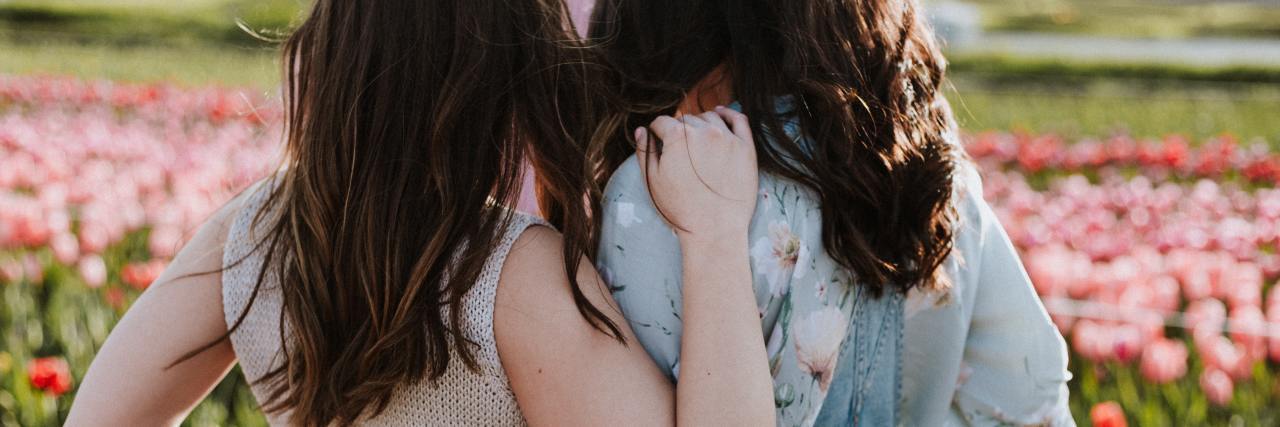 Read This When Depression Makes You Feel Unlovable photo of two women behind, arms around each other, standing in front of a field of flowers