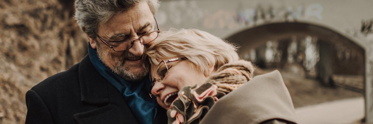 photo of middle aged couple standing close to each other, smiling and happy