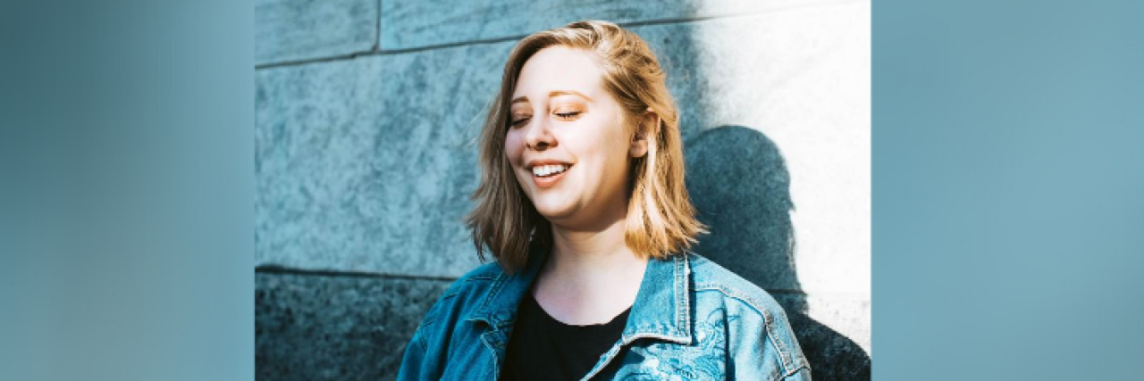 Understanding My Self-Worth as the Key to My Eating Disorder Recovery Woman in denim jacket, leaning against a wall with eyes closed