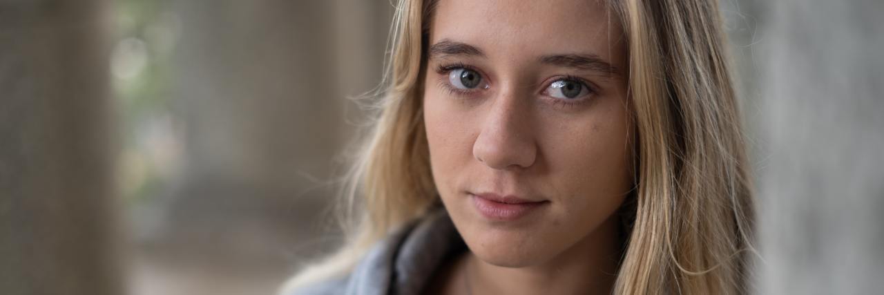 How I've Changed in the Years Since My Schizophrenia Diagnosis photo of woman leaning against corner of a wall looking into camera with a slight smile