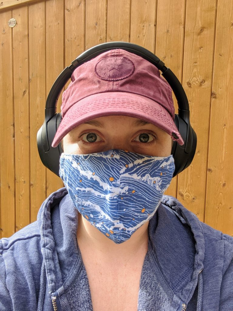 photo of the contributor wearing a patterned face mask, baseball cap and headphones while looking into the camera