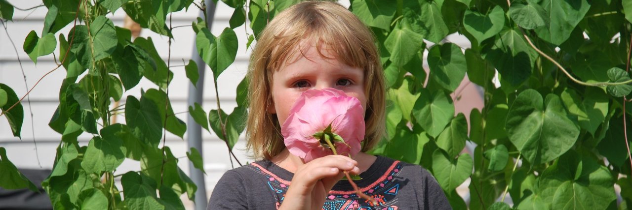 Raising My Daughter With Ehlers-Danlos Syndrome Emily's daughter smelling a flower.