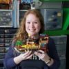 the author holding a Lego boat that she made, smiling