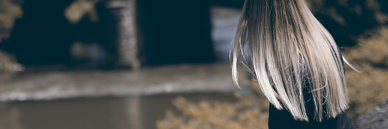What COVID-19 Has Taught Me About My Social Anxiety photo of woman sitting on wall or bench, looking away from camera