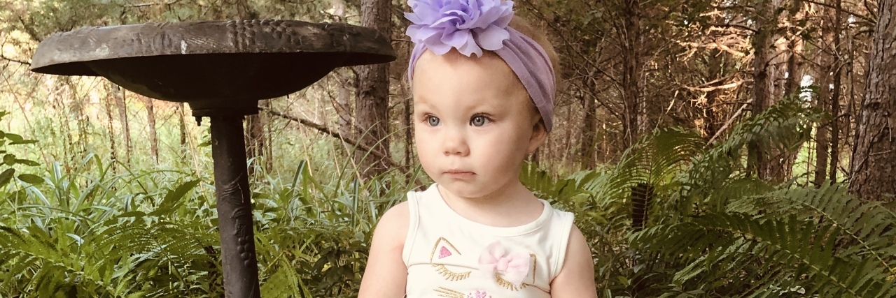 Pediatrician Isn't Taking Child's Health Concerns Seriously The author's baby sitting on a rock, with a purple bow in her hair