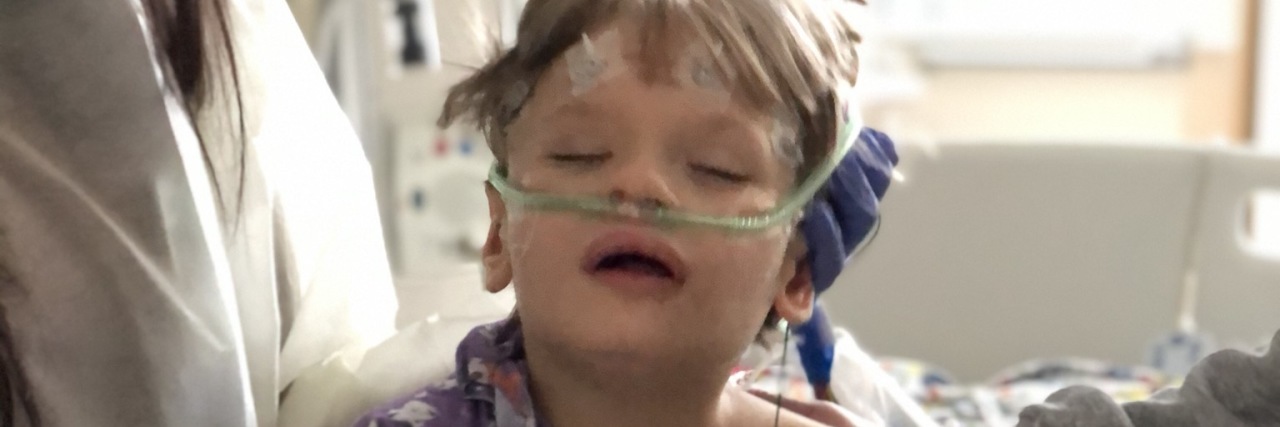 The author's child, sitting on a hospital bed with a blood pressure cuff, oxygen, and heart monitor nodes