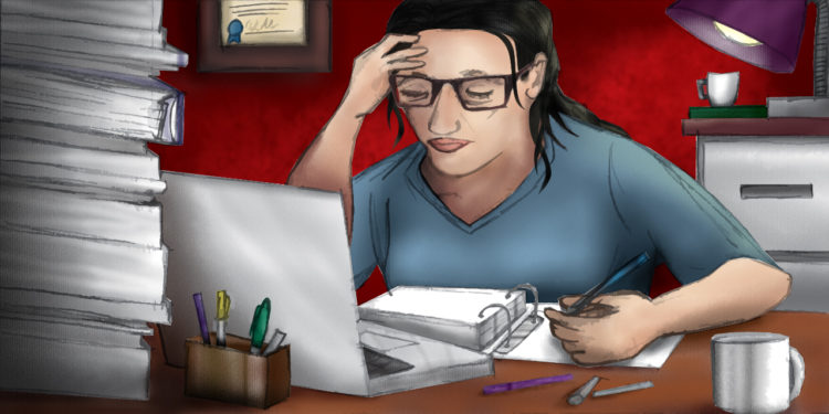 Stressed female therapist works on paperwork on her computer surrounded by piles of books