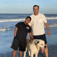 Michelle's son and his dad with their dog on the beach.