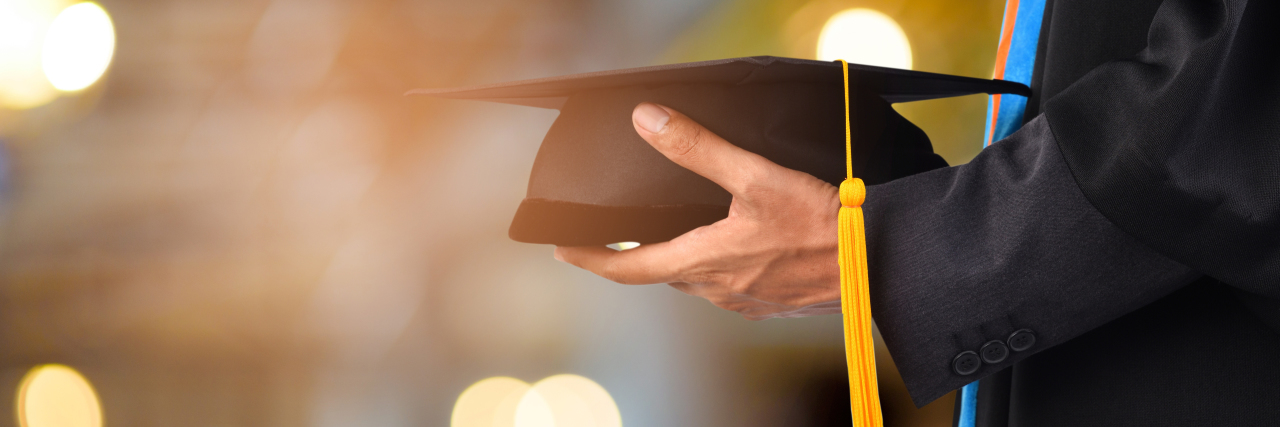 5 Lessons From Completing High School With Fibromyalgia Young man holding graduation cap.