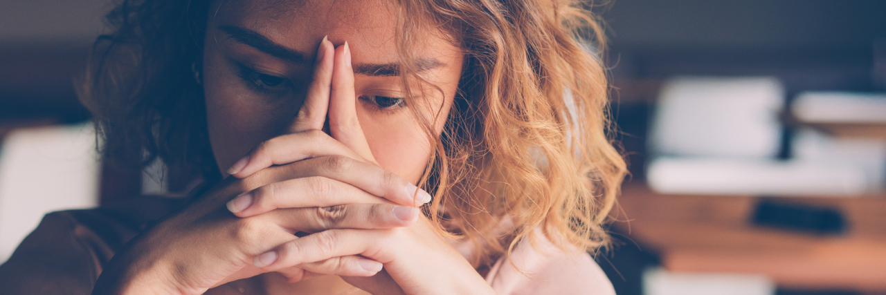 photo of stressed or upset woman resting her head on her hands, eyes closed