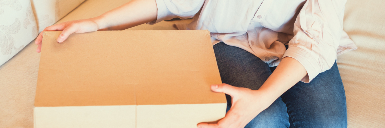 woman sitting on the couch getting ready to open a cardboard box