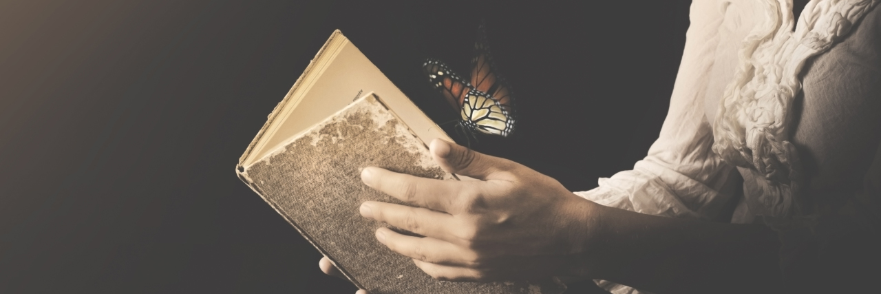 Creating New Dreams in Life With Chronic Illness Woman holding an open book with a butterfly flying out of it.