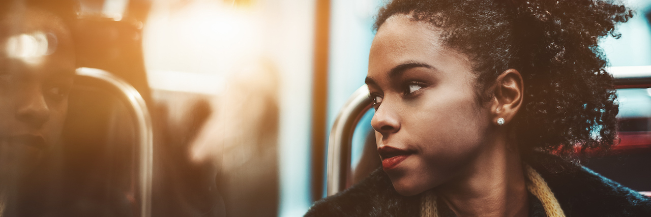young woman pensively looking outside the carriage window while sitting in a metro train