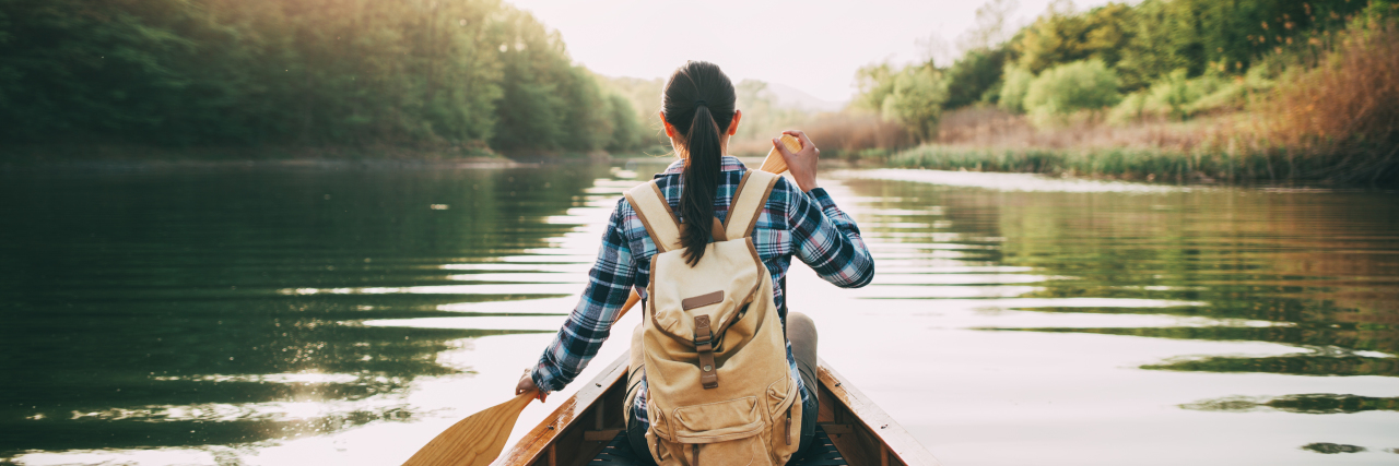 Young woman backpacker canoeing.