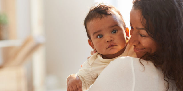5 Things You Should Know About Klippel Feil Syndrome Smiling loving young mom with curly hair standing in room and holding adorable baby boy with chubby cheeks