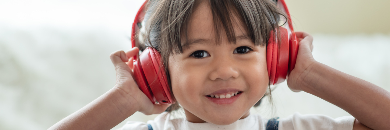 Happy Asian child enjoying listening to music with headphones