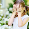 Cute little girl covering her face with her hands, with a frowny face drawn on her hand