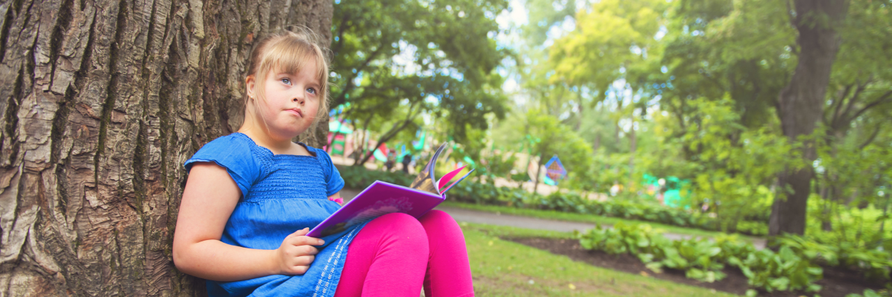 When Medical Staff Make Insensitive Comments About Down Syndrome Girl with Down syndrome sitting under a tree reading a book.