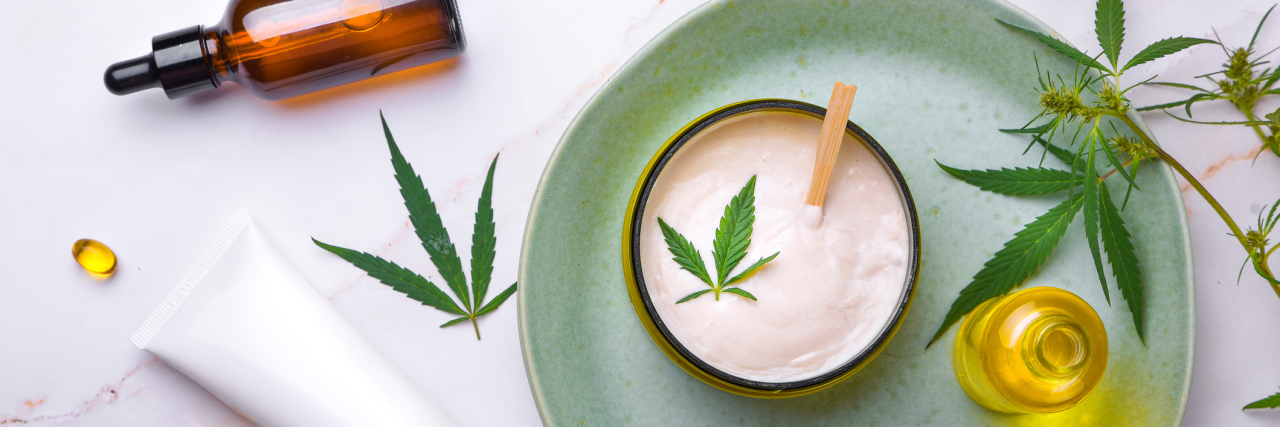 What Are the Ways You Can Take CBD? Cosmetics with cannabis oil on a turquoise plate on a light marble background.