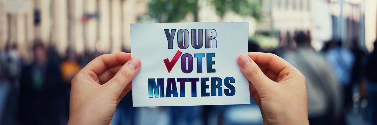 Hands hold a paper sheet with the message "Your vote matters."