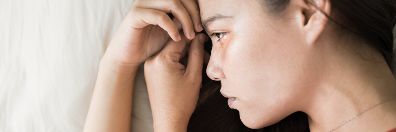 Managing the Pain/Anxiety Cycle With Endometriosis Woman in pain lying in bed.