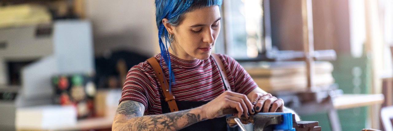 4 Small Businesses Run By People With Autism Young woman doing woodwork in a workshop.