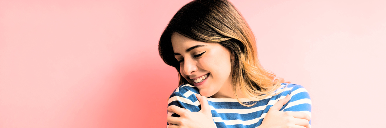 Prioritizing My Well-Being as a Young Adult With a Disability Young woman hugging herself.