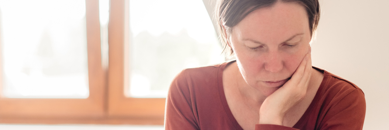 I 'Should' Be Happy but Bipolar Is Making Me Depressed photo of woman at home with phone and laptop, looking stressed