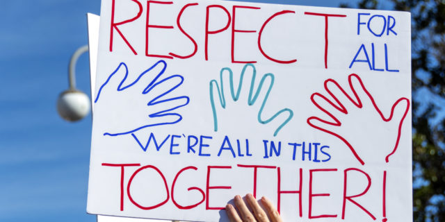 Close-up of a hand-drawn sign proclaiming, "Respect for All. We're All in this Together!"