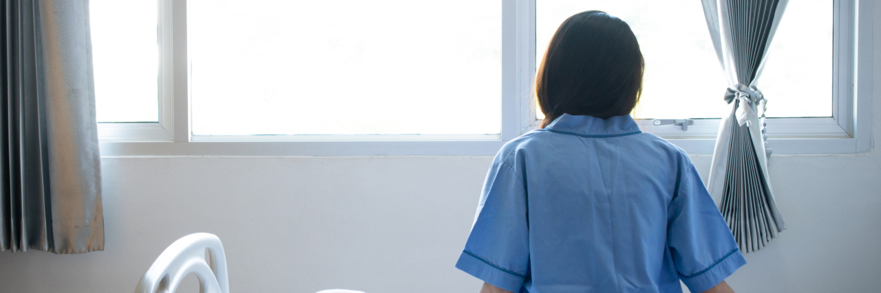 My 3 Weeks in the Psychiatric Hospital A woman sitting in a hospital bed facing the window