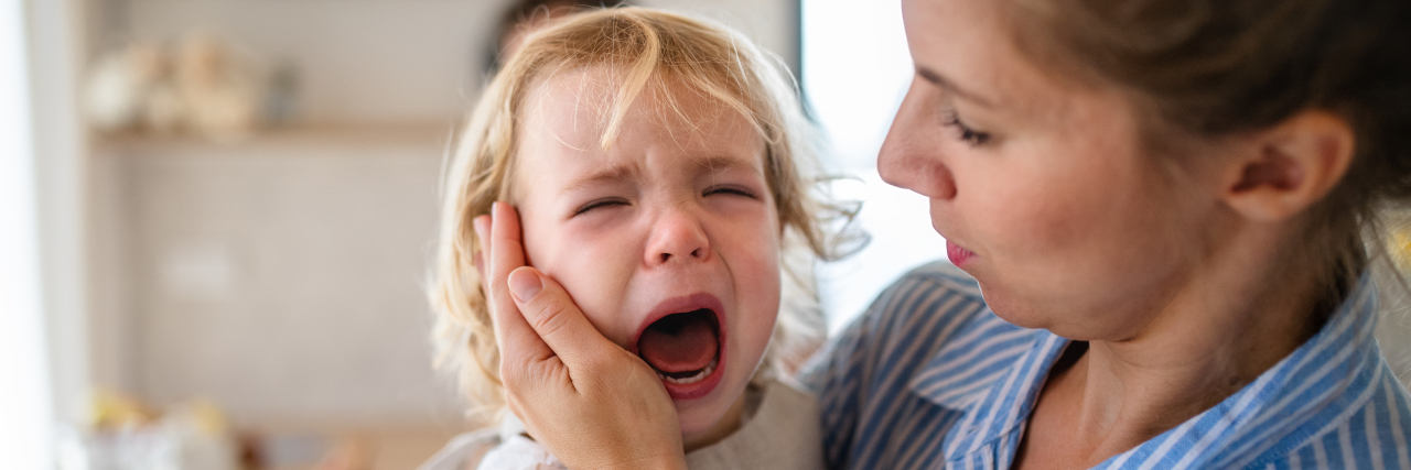 7 Strategies to Help Autistic Children Manage Meltdowns Mother holding crying child.