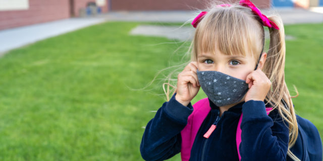 Girl wearing a mask and school backpack.