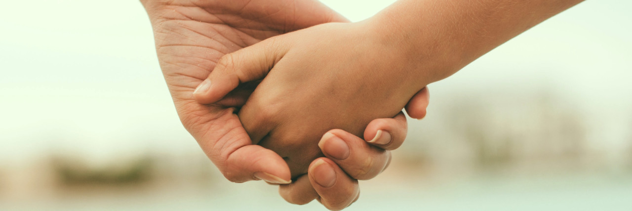 What I Wish People Knew About Epilepsy Mother holding hand of her daughter -- close up of hands