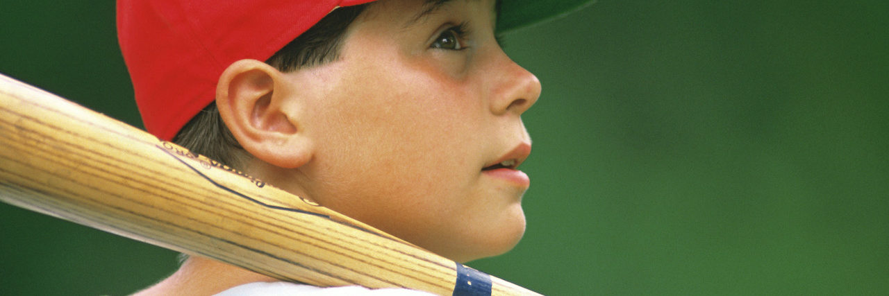 A young boy in a red hat holding a baseball bat