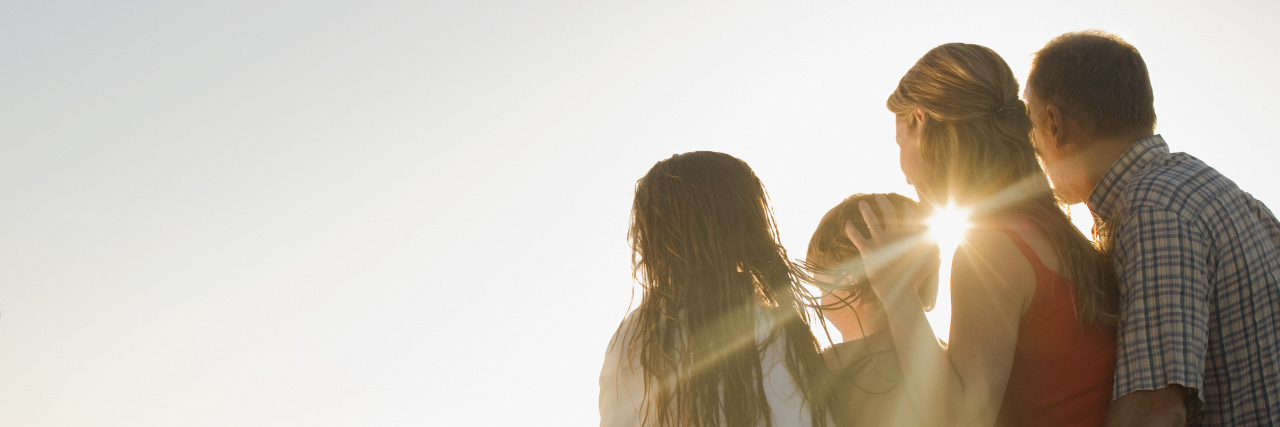 Parenting Kids With Chronic Conditions During the COVID-19 Pandemic Family sitting on deck in afternoon sun.