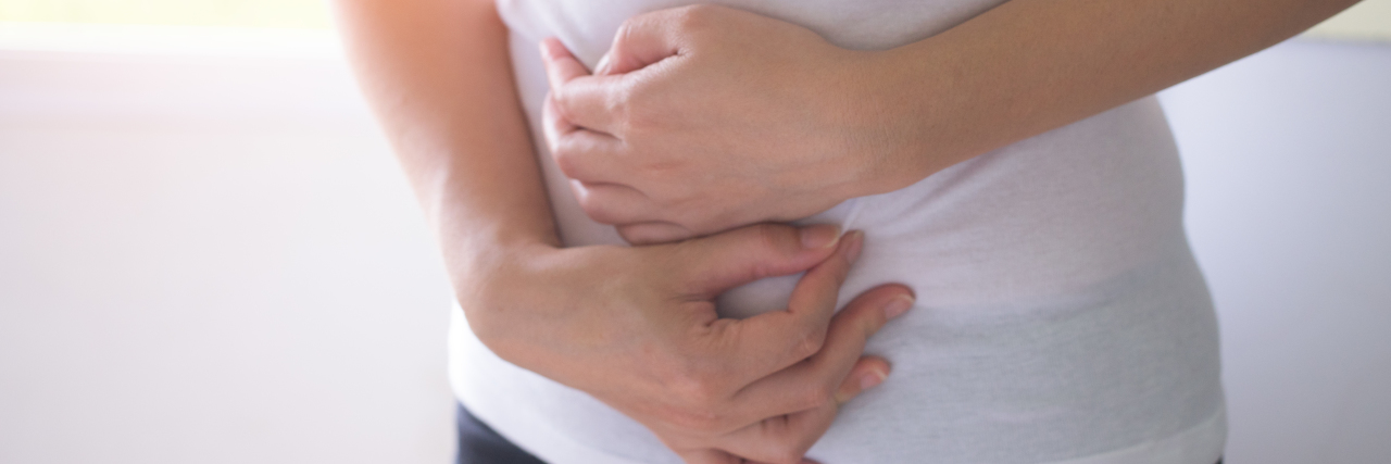 What It's Like to Live With Abdominal Spasticity After a Brain Injury Woman holding her stomach.