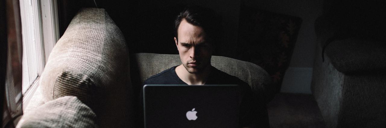 Self-Care for Schizophrenia photo of man sitting on sofa beside a window with a laptop on his knees