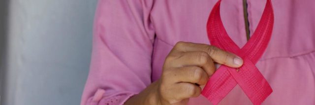 A woman holding a pink ribbon