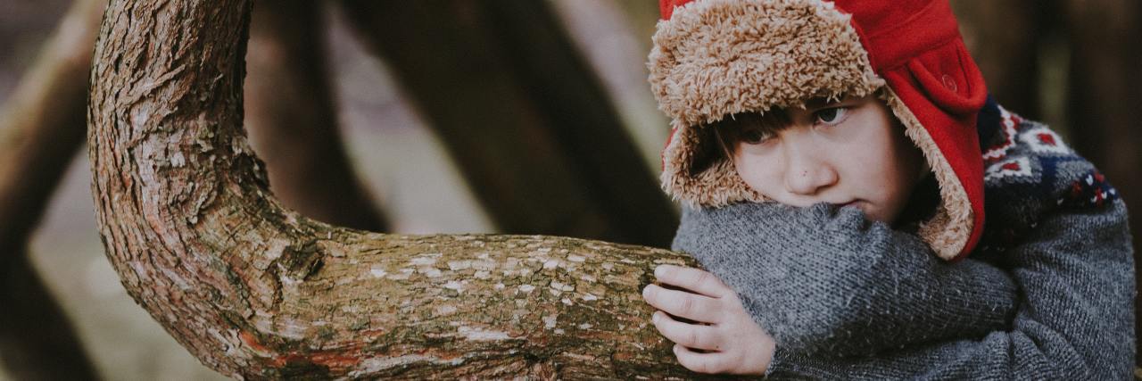 The Common Ways To Spot an Anxiety Disorder in Your Child photo of upset looking boy resting his arms and head on a tree branch