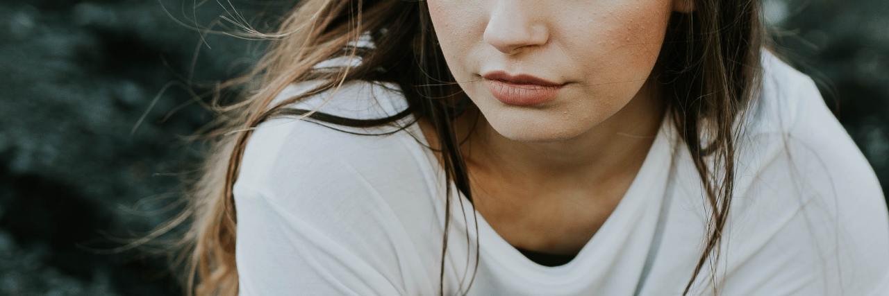 Disproving My Family Myths for My Mental Health and Trauma Recovery photo of woman close up, hugging knees and looking throughtful