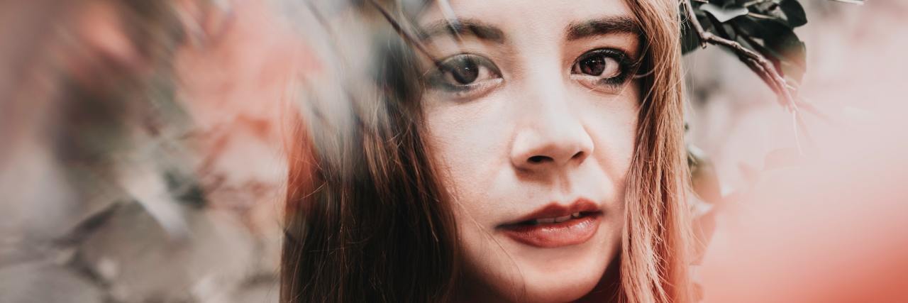 Dissociation Is Not Always a Mental Illness A woman standing next to flowers, which are blurred