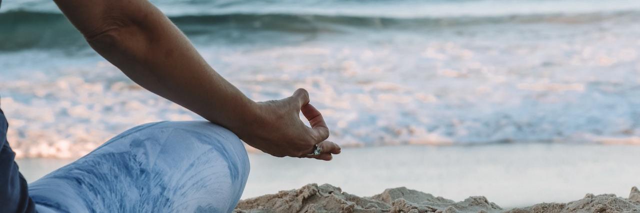 'Mindful As F*ck' Book Excerpt: 'Let It Go' Mindfulness Skill Woman with legs crossed wearing yoga pants meditating on the beach