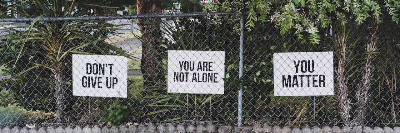 Signs saying "Don't give up," "You are not alone" and "You Matter"