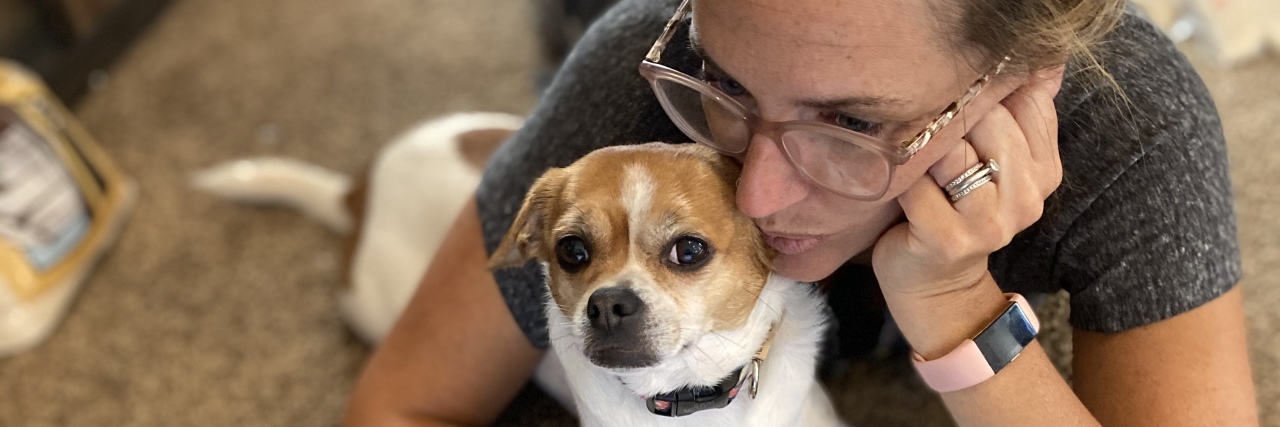 photo of contributor lying on the floor with her dog between her arms and her laptop in front of her