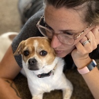 photo of contributor lying on the floor with her dog between her arms and her laptop in front of her