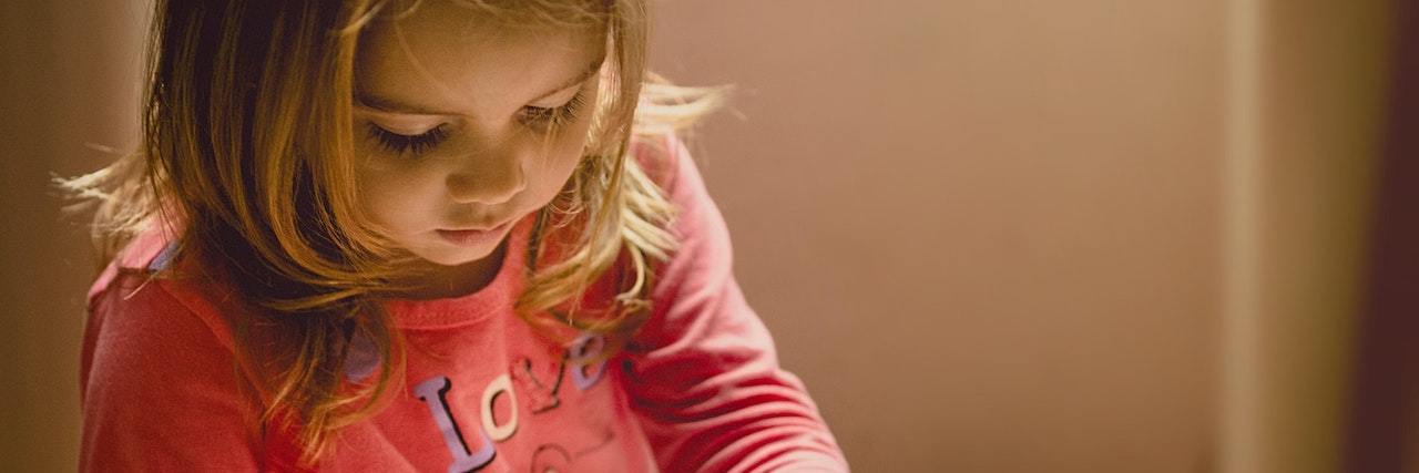 Transcending the Pain of the Past By Loving Yourself Now Young child looking down and reading a book